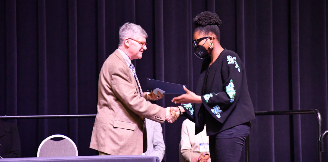URF student accepting their award for a winning presentation from a UIC faculty member